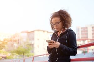 Garota ouvindo música em fones de ouvido usando celular