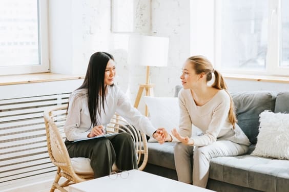 Mulher sentada em sofá conversando com psicóloga