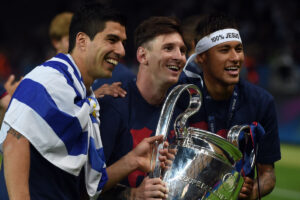 Neymar ao lado de Surez e Messi, com os trs segurando a taa da Champions League (foto: AFP PHOTO / PATRIK STOLLARZ)