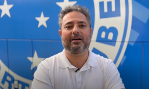 Alexandre Mattos falando em frente ao escudo do Cruzeiro (foto: Divulgao/Cruzeiro)