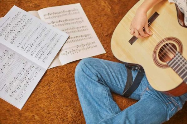 Estudante de música tocando violão e lendo partituras